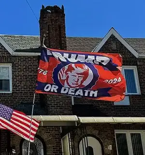 A flag reading Trump or Death hanging from the face of a building.